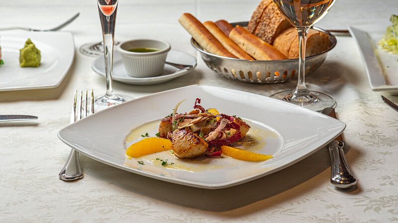 Seared sea scallops with basket of bread and glass of white wine