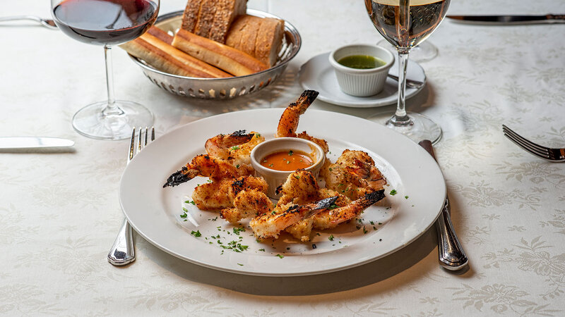Plated jumbo shrimp with a basket of bread and glass of white wine
